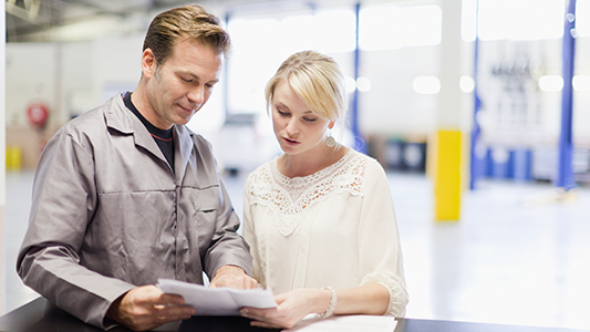 An auto mechanic going over paperwork with a client.
